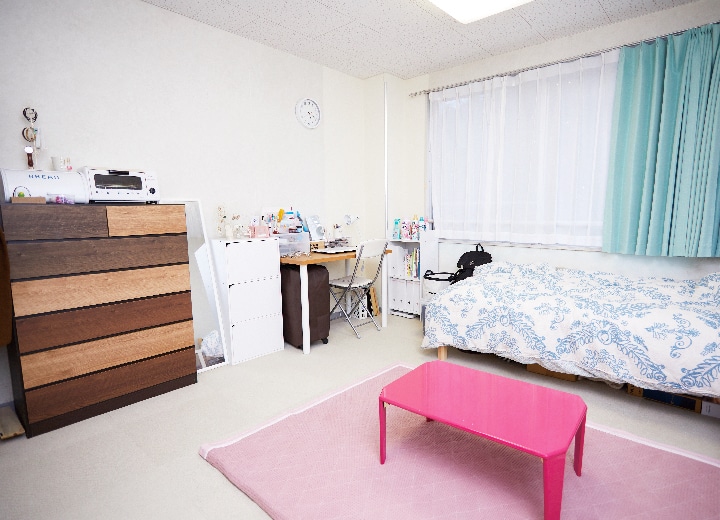 写真：女子寮の個室。部屋にはベッドや勉強机、ローテーブル、タンスなどが置かれている。