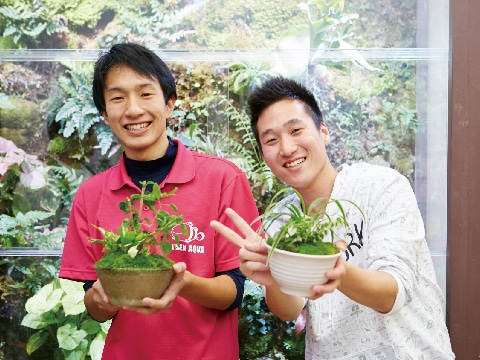 鉢植えを持つ２人の男子学生